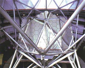 El espejo hexagonal del telescopio Hobby-Eberly de 11m colocado en el armazón del telescopio. Abajo a la izquierda, quizás, se observen dos personas junto a la base del telescopio. Foto: © Universidad de Texas en Austin.